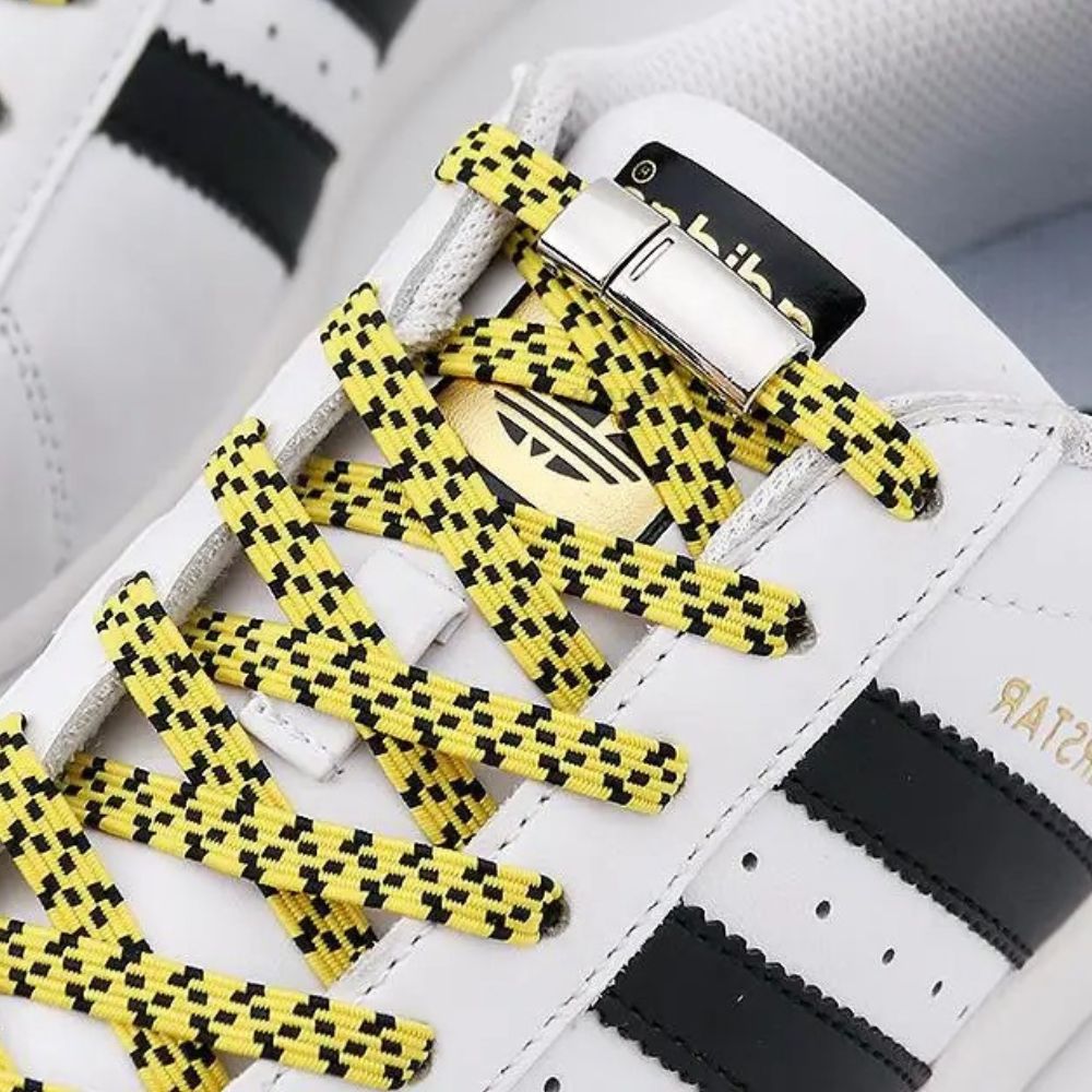 Zijaanzicht van gele pixel platte elastische veters met zwarte stippen met magneetsluiting voor een opvallende stijl zonder strikken